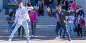 两个希腊学生在外面跳舞，学生们在后面看着